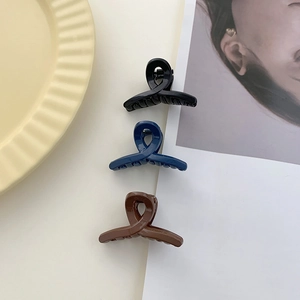 Close-up of small solid color mini hair claws in black, deep blue, and brown resin