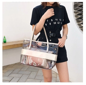 Detailed macro of transparent PVC tote bag with champagne gold metallic frame and handle