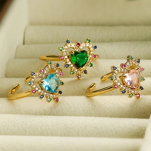 Three 18K gold plated heart-shaped zircon rings in green, blue, and pink on velvet