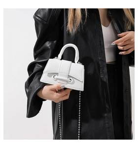 Detailed view of mini white leather bag with beaded chain and silver ball handle