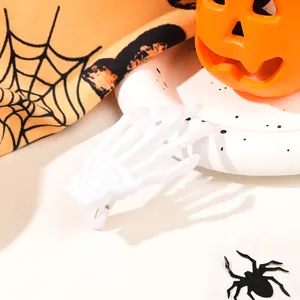 Macro shot of white skeleton hand hair clip on Halloween pumpkin and spider web backdrop