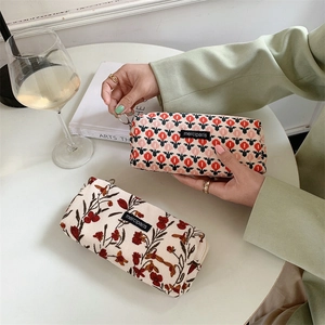 Floral corduroy cosmetic pouches with zippers on a desk with elegant lifestyle accessories