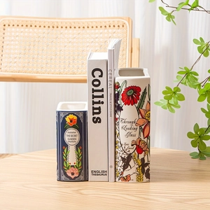 Detail of book-shaped ceramic vase featuring vintage floral patterns and garden book titles
