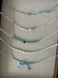 Détail de colliers de perles avec nœuds bleus, cœurs et perles colorées sur velours gris