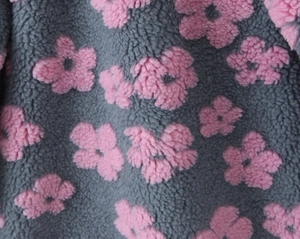 Detail of plush lamb wool fabric with grey base and pink floral embroidery pattern