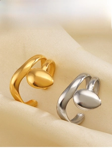 Close-up of gold and silver liquid metal teardrop open rings on silk fabric