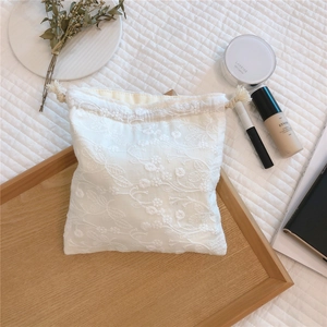 Macro detail of white lace embroidery and cotton drawstring closure on the storage bag