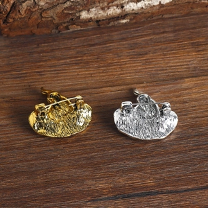 Vintage witch hat brooches in gold and silver finishes on a rustic wooden background