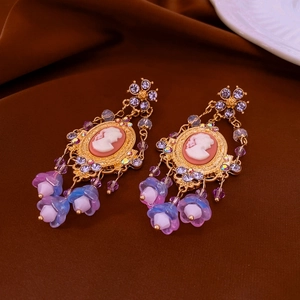 Detailed close-up of vintage gold earrings with cameo portraits and crystal floral tassels