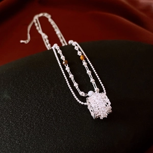 Detail of silver double-layer necklace with hollow zircon cylinder and tiger eye beads