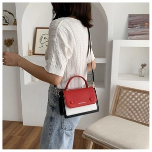 Close-up of tricolor patchwork shoulder bag with red flap and white body on a model