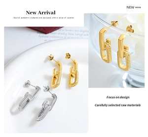 Macro shot of U-shaped gold and silver chain link earrings on glassware background