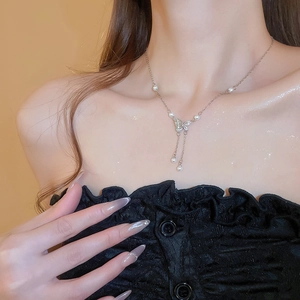 Close-up of Y2K butterfly pendant with sparkling zircons and delicate pearl tassels