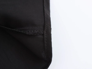 Close-up of high-quality stitching on a black V-neck long-sleeve blouse edge