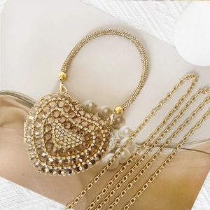 Detail of a heart-shaped evening clutch with champagne rhinestones and a gold chain