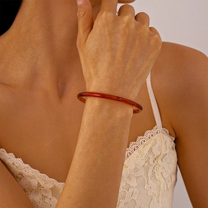 Gros plan détaillé d'un bracelet jonc en résine ambre translucide porté au poignet