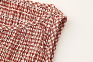 Détail du tissu vichy rouge et blanc avec des plis smockés sur la zone de l'épaule