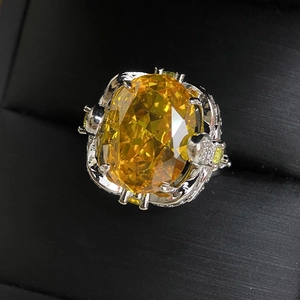 Close-up of luxury 18k plated ring with large oval yellow gemstone in a textured box