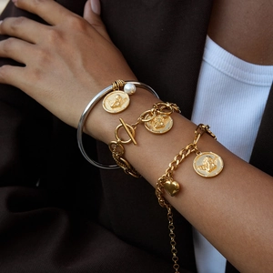 Vintage gold coin charm bracelet with angel relief and layered chains on female wrist