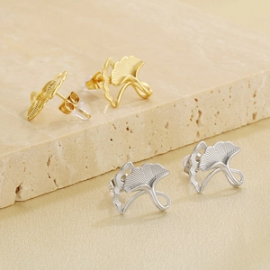 Ginkgo leaf stud earrings in gold and silver finish on natural stone background