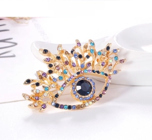 Close-up of retro eye brooch with blue crystal pupil and colorful rhinestones