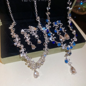 Close-up of flower pendant necklace and earrings set with blue crystals in black box