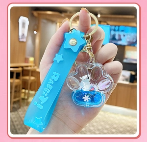 Detail showing blue cat claw keychain with floating liquid sand and rabbit charms