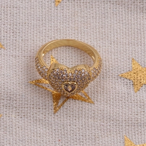 Détail de la bague coeur dorée avec micro-pavé de zircones sur un tissu tissé
