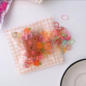Detail view of colorful high-elastic hair bands in a cute frosted bear zipper storage bag