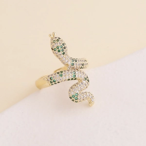 Macro detail of gold snake ring with micro-paved green and white cubic zirconia
