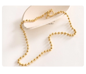 Close-up of golden beaded necklace featuring a vintage OT toggle clasp and polished finish