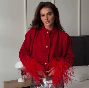 Detailaufnahme der roten Strickjacke mit flauschigen Federbündchen und Goldknöpfen