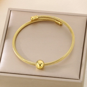 Close-up of golden cable wire twisted bangle with polished bead and striped end caps