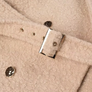 Detail of beige lamb wool coat featuring premium metal buttons and waist belt buckle