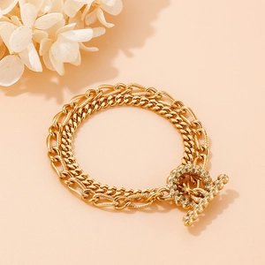 Close-up of gold layered chain bracelet featuring a rhinestone encrusted T-bar clasp
