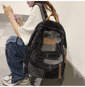 Detail of retro patchwork denim backpack featuring brown leather zipper pulls and logo tag