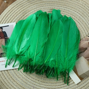 Close-up of vibrant emerald green goose feathers on a woven mat for DIY crafts and decor