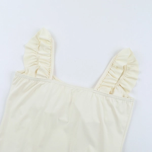 Detail of ruffle shoulder straps on a pale yellow square neck mini dress with sleek finish