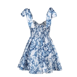 Détail de robe florale bleue et blanche montrant bretelles nœuds et taille froncée