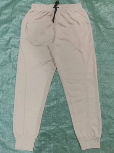 Dettaglio dei jogger beige con vita elastica regolabile e coulisse nere sportive