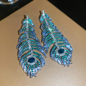 Macro shot of luxury feather earrings with deep blue crystals and shimmering rhinestones