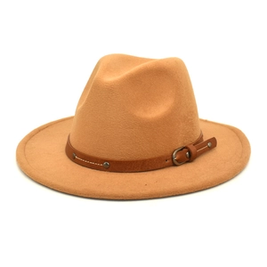 Macro detail of camel wool fedora hat featuring a brown leather band and metallic buckle