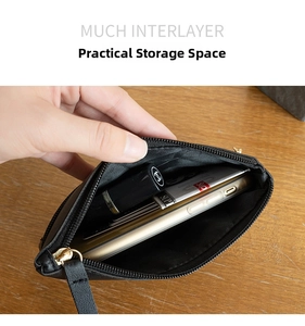 Detail of black pebbled leather clutch with multiple interior compartments and gold zippers