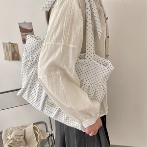 Detailansicht der großen weißen Canvas-Schultertasche mit blauen Punkten und Falten