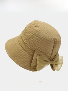 Detailed close-up of khaki bucket hat featuring a delicate mesh bow and textured fabric