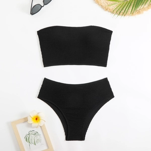 Detailed flat lay of black crinkle fabric bikini set with summer vacation accessories