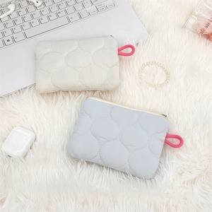 Close-up of quilted cotton sanitary bags in beige and grey on a cozy white plush rug