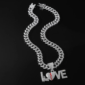 Macro detail of iced-out LOVE pendant with red lightning heart on silver cuban chain