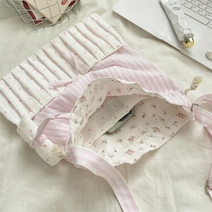 Detail of the pink and white striped shoulder bag showing its floral lining and inner pocket