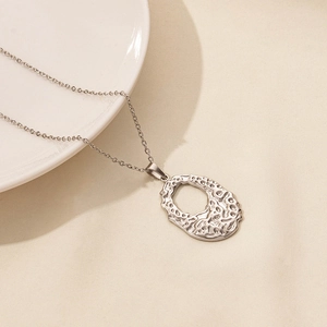 Macro detail of silver cutout oval pendant featuring natural lava texture on a fine chain